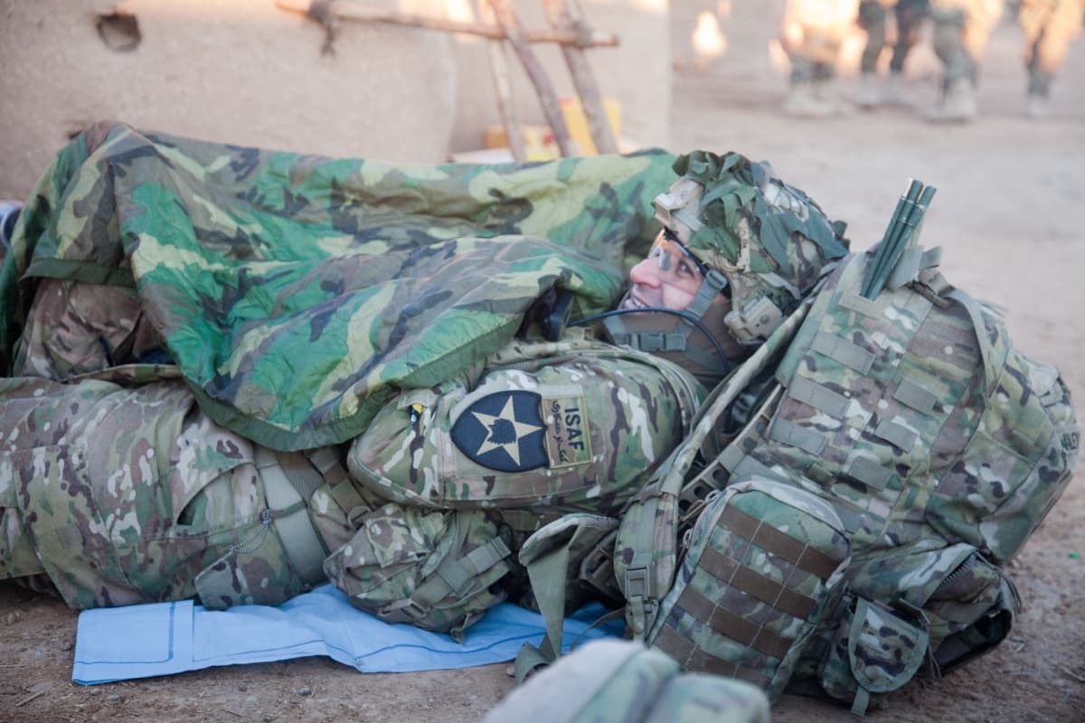 Military camping gear including tactical tent, woobie blanket, mess kit, and entrenching tool