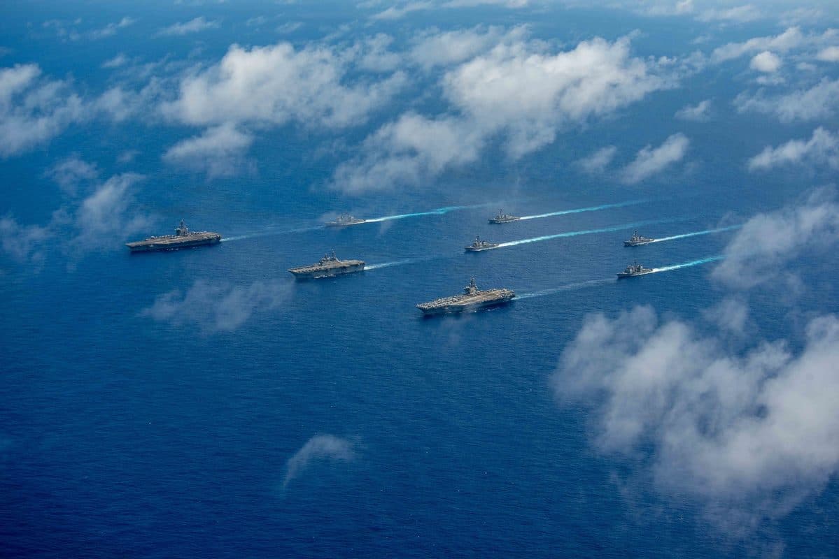 Multiple U.S. Navy warships sailing in formation as part of a carrier strike group exercise in the Pacific Ocean