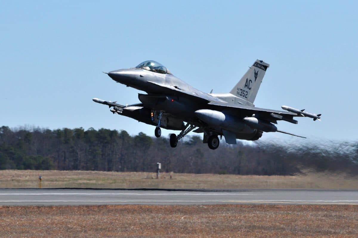 F-16 Fighting Falcon taking off in full afterburner from an Air National Guard base, flames visible from the engine nozzle