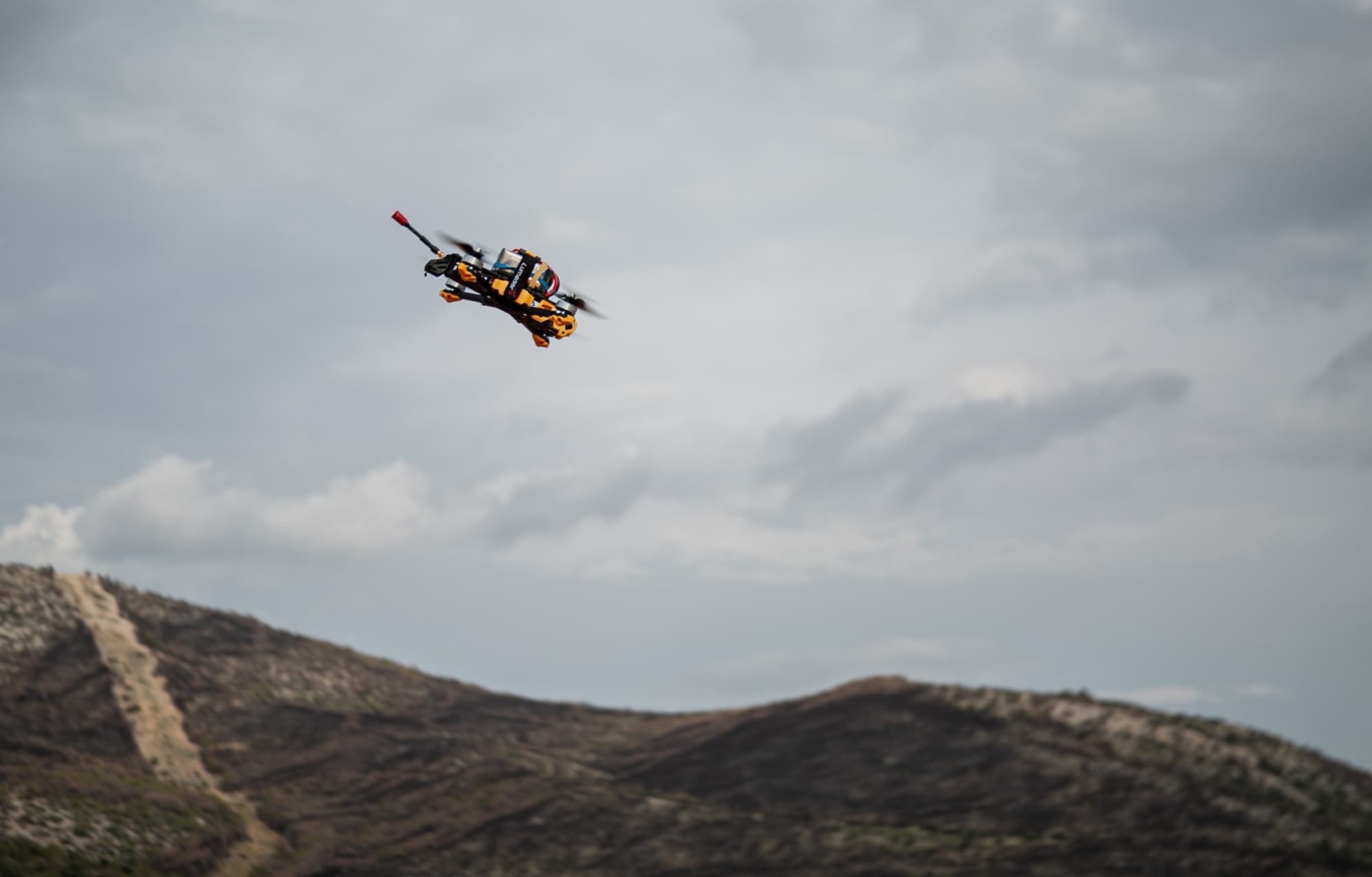 A first-person-view military drone in flight over a battlefield
