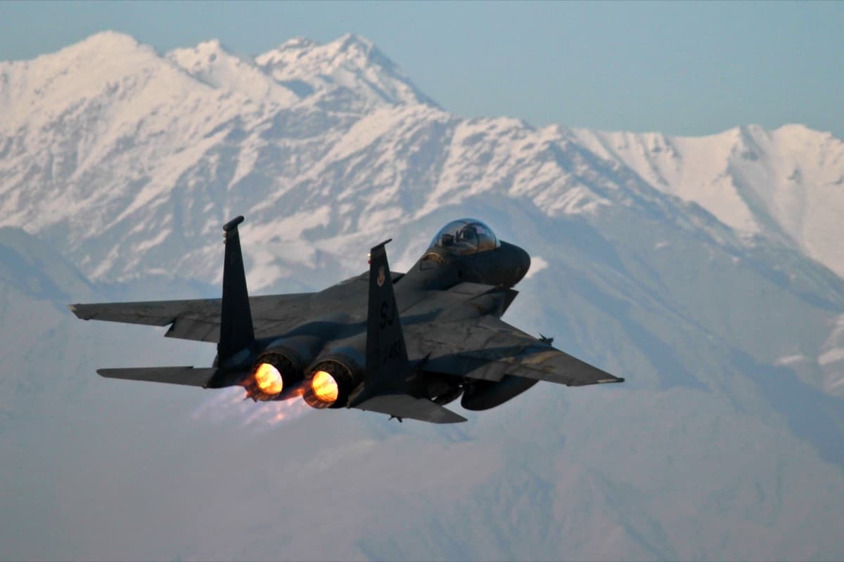 U.S. Air Force F-15E Strike Eagle climbing in full afterburner against a mountain backdrop