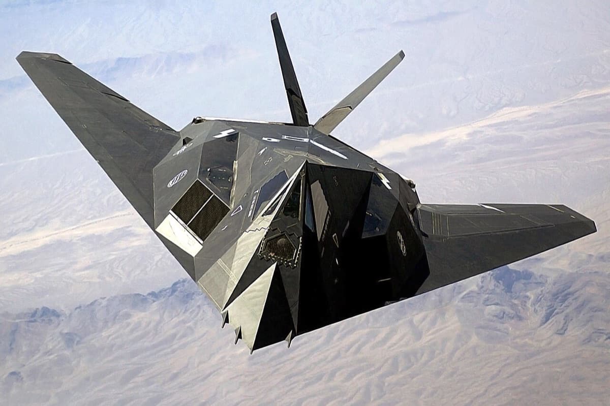 F-22 Raptor climbing through clouds demonstrating the curved stealth shaping of fifth-generation fighter design