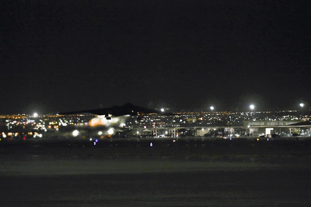 B-2 Spirit stealth bomber taking off at dusk, silhouetted against the lights of Las Vegas at Nellis Air Force Base