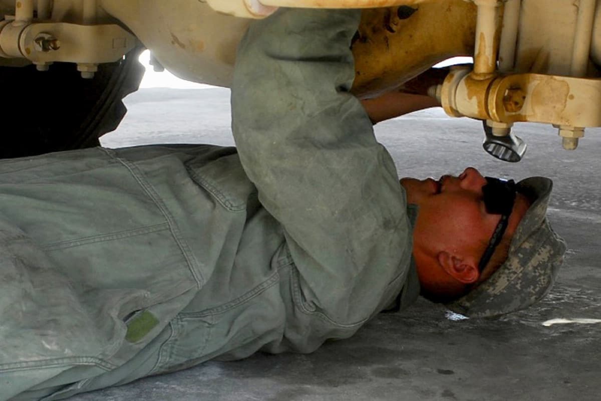 U.S. soldier performing maintenance on an MRAP vehicle at a forward operating base in Afghanistan