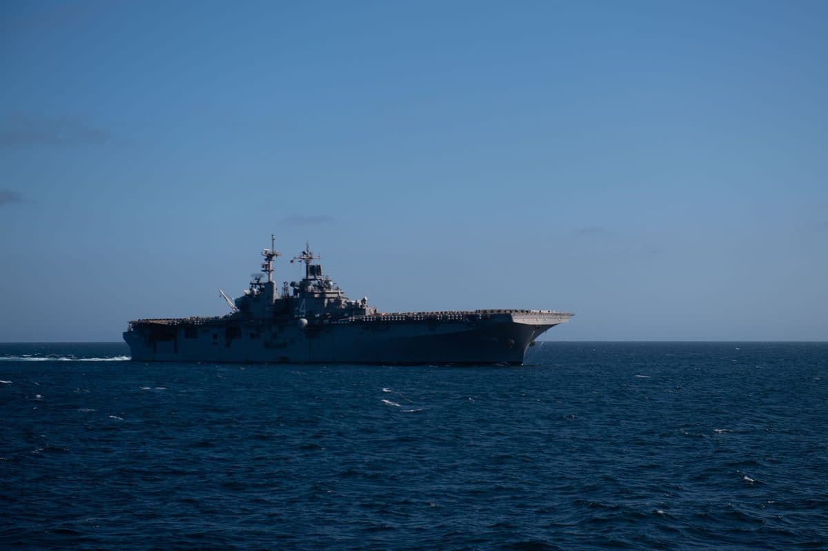 Wasp-class amphibious assault ship at sea with helicopters on the flight deck and the well deck visible at the stern