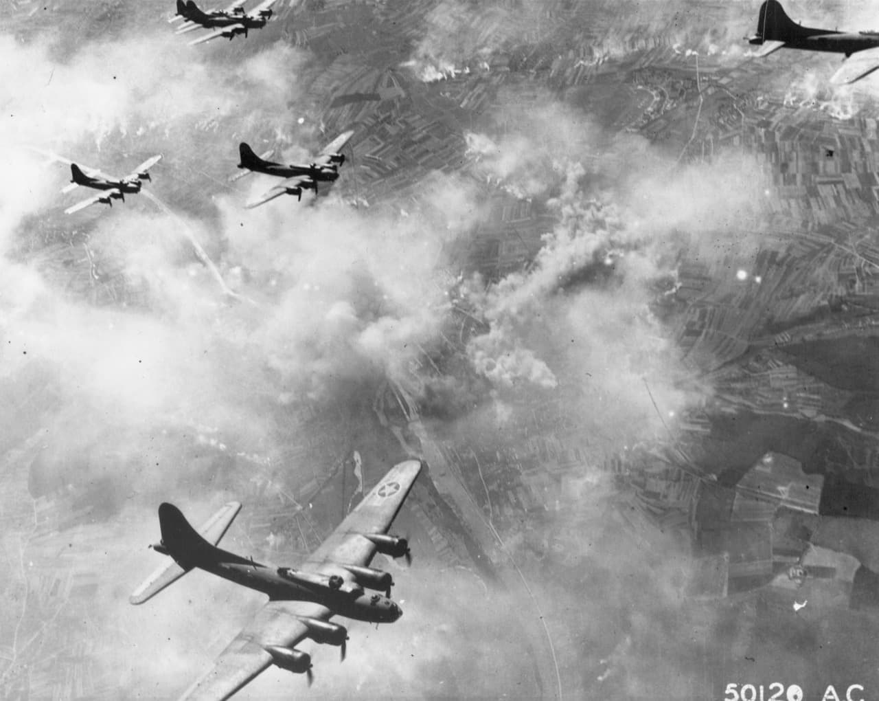 B-17 Flying Fortresses in combat box formation over Europe with smoke rising from targets below, 1943