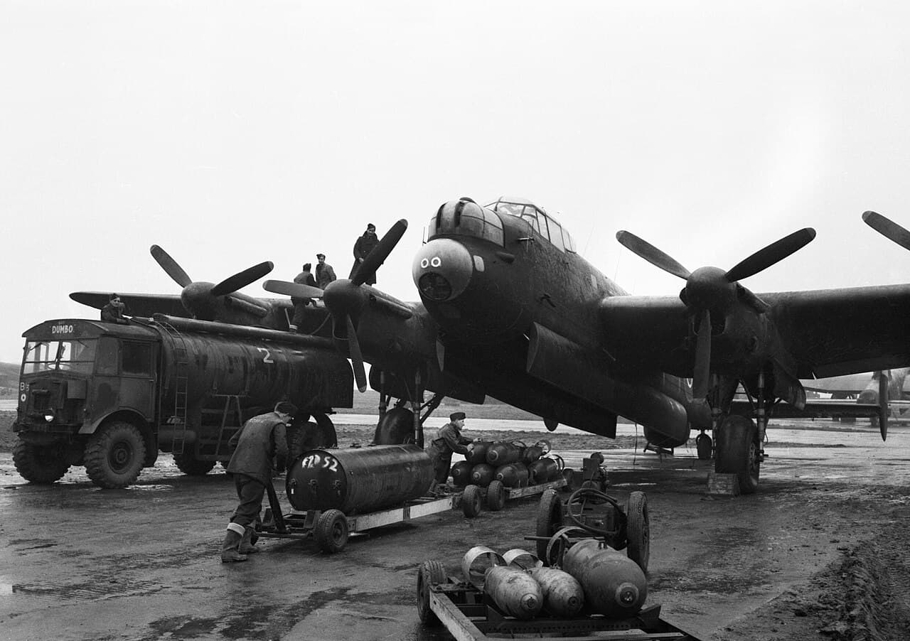 Lancaster bomber being loaded with bombs by ground crew before a night mission, fuel truck "Dumbo" visible