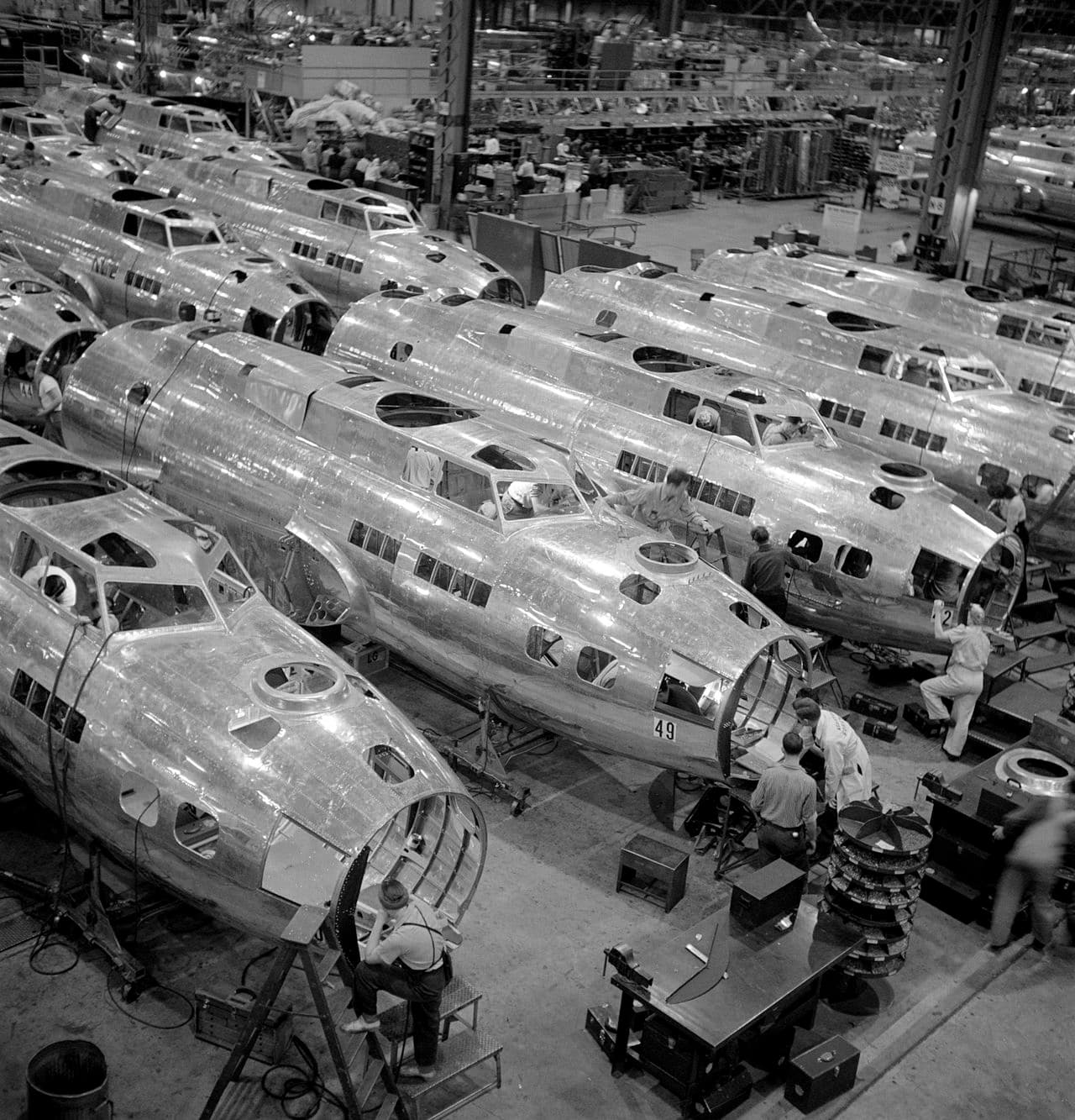 B-17 Flying Fortress fuselages being assembled on a factory floor with workers visible