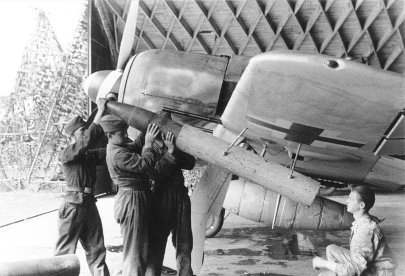 Ground crew loading ordnance under an Fw 190's wing on a Luftwaffe airfield