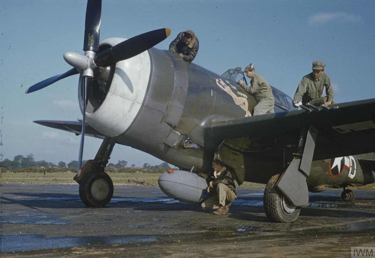 Ground crew servicing a P-47 Thunderbolt at an English airfield, showing the massive R-2800 radial engine