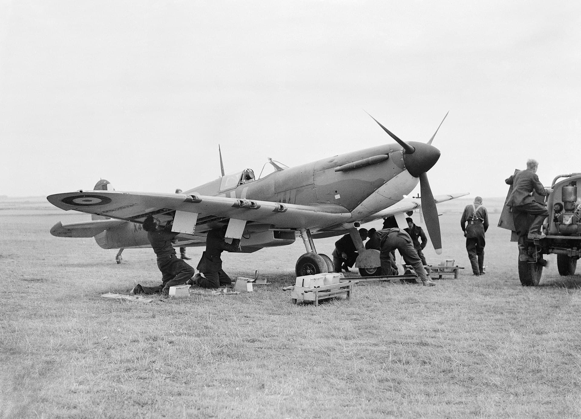 RAF ground crew rearming a Spitfire with ammunition boxes on the ground