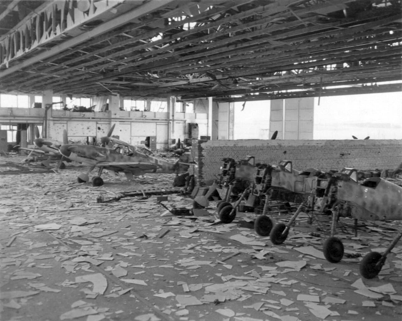 Bf 109Gs in a damaged hangar at Detmold airfield, Germany, April 1945