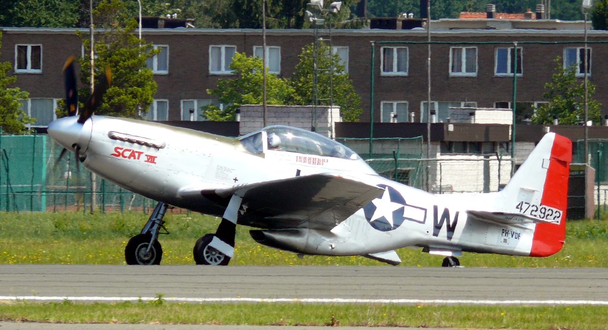 P-51D Mustang in flight with invasion stripes over European countryside