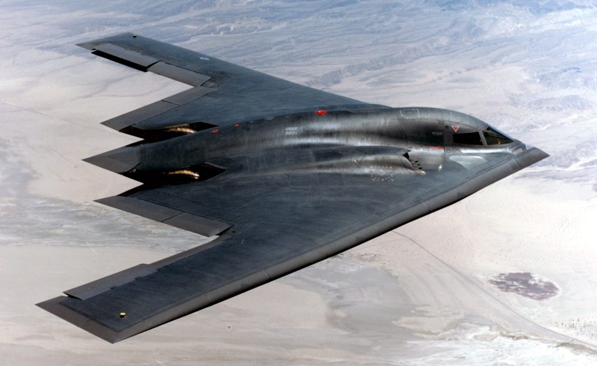 B-2 Spirit stealth bomber flying wing silhouette against cloudy sky
