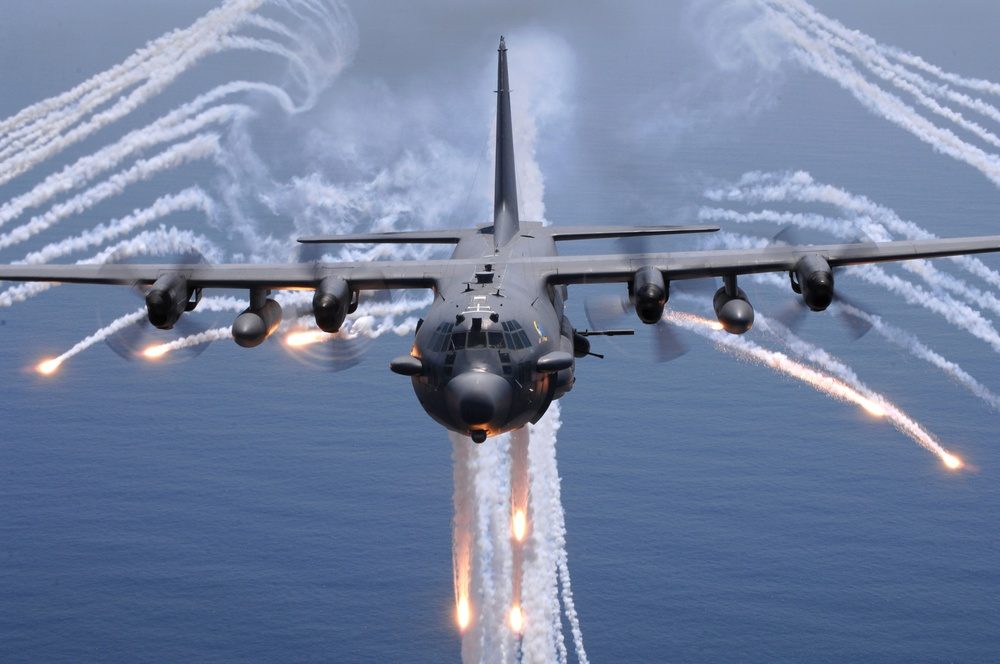 AC-130 gunship deploying flares over the ocean during night operations