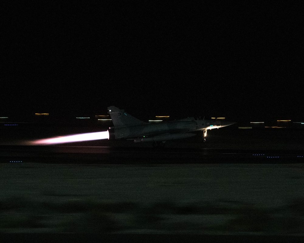 Fighter jet in full afterburner at night with vivid flame plume from exhaust nozzle