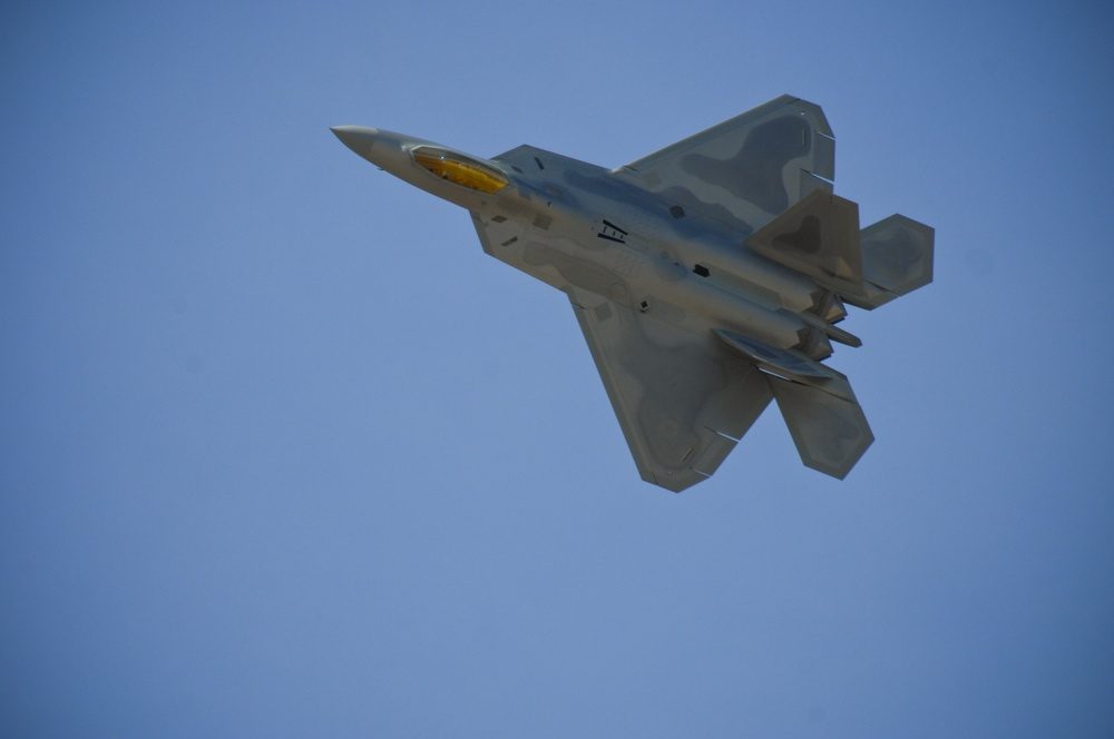 F-22 Raptor flying in formation during a heritage flight demonstration, showcasing the aircraft's sleek stealth design