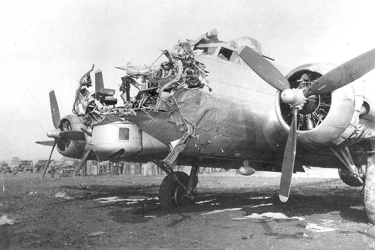 B-17 bomber with severe battle damage to the nose and fuselage demonstrating its legendary toughness