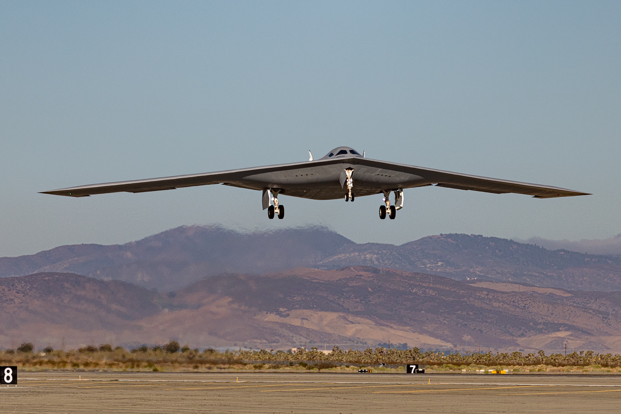 B-21 Raider viewed from below during a test flight, showing the clean flying wing design