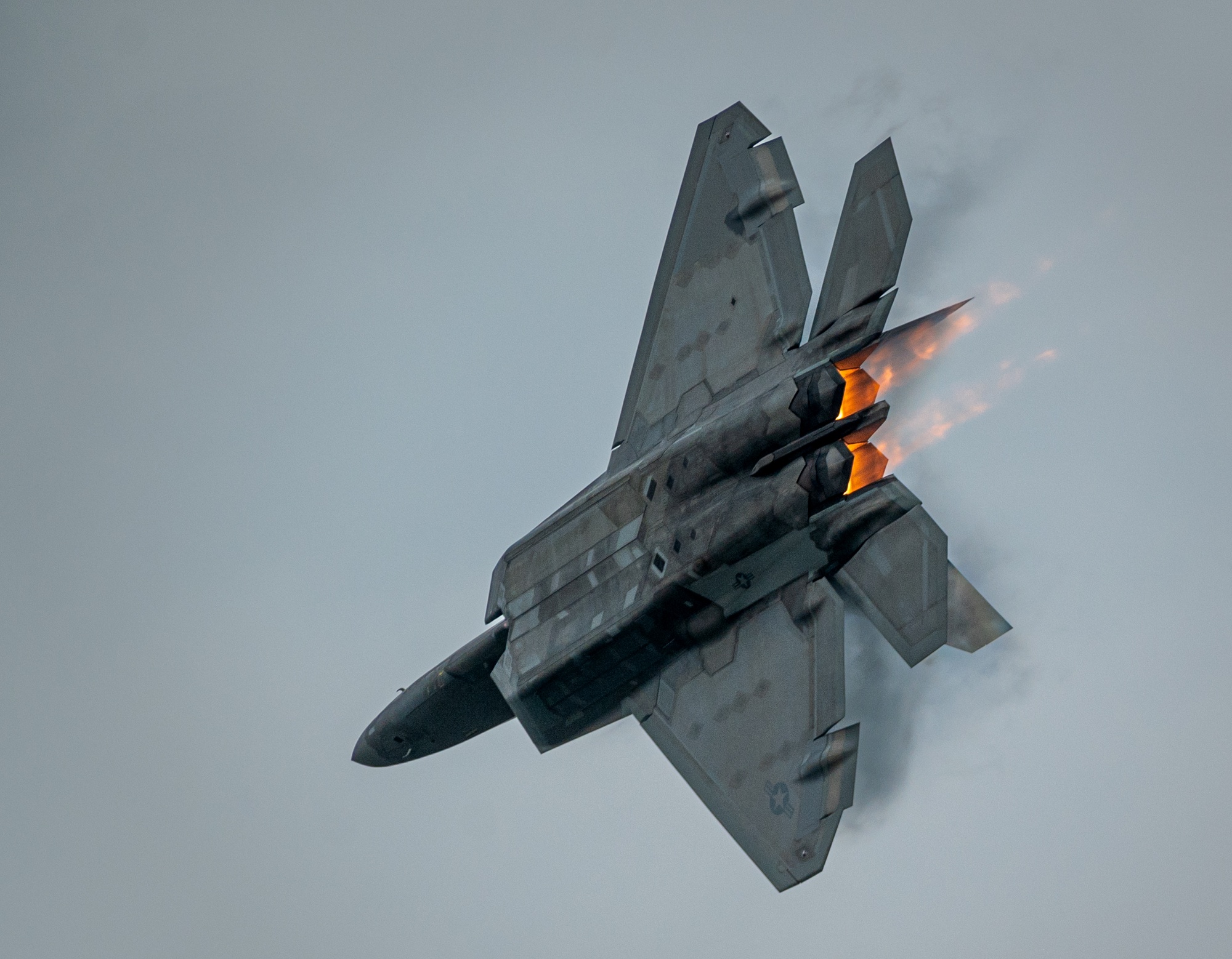 F-22 Raptor banking over snow-capped mountains during a training mission