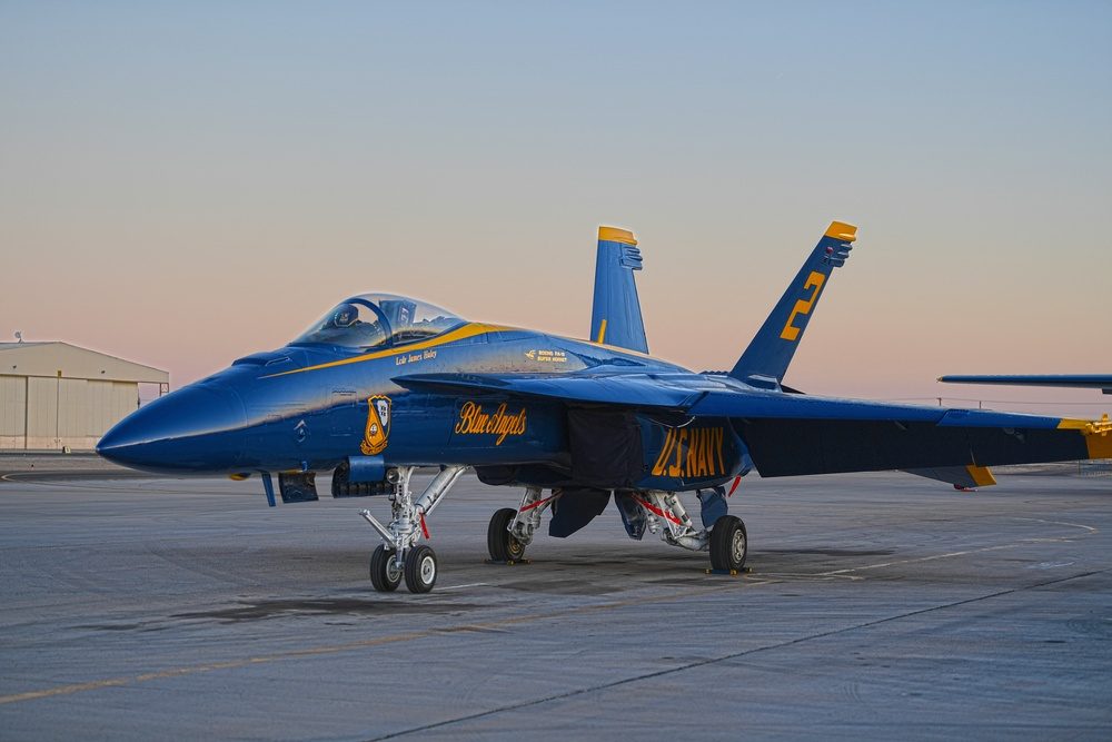A Blue Angels F/A-18 Super Hornet in flight over a desert landscape