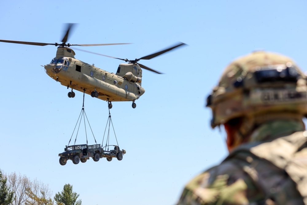 CH-47 Chinook helicopter transporting a vehicle via external sling load during Mountain Peak training exercises