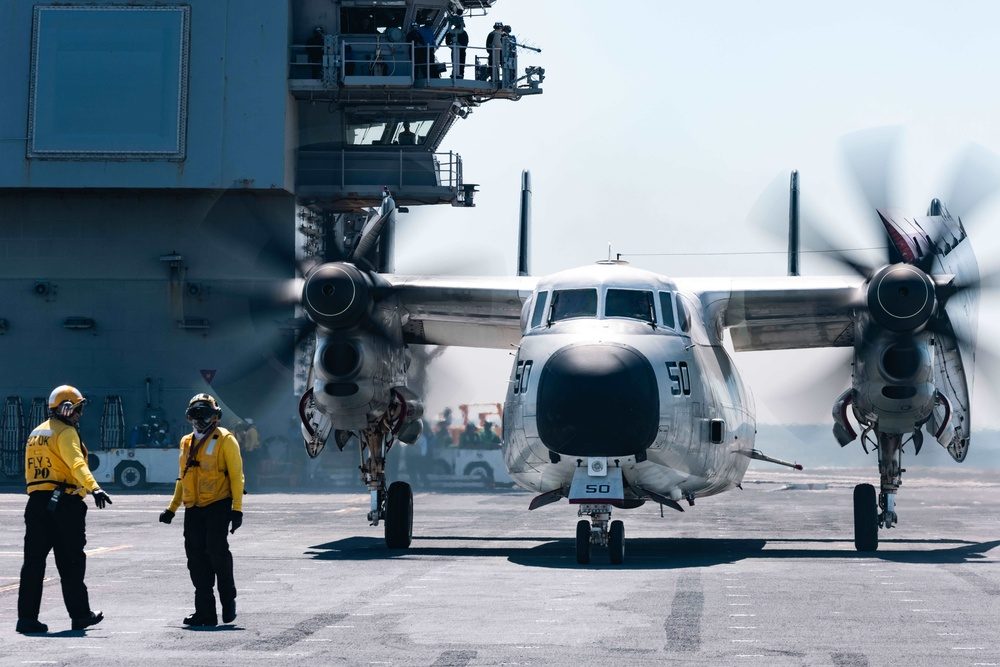 Night flight operations on a carrier deck with aircraft illuminated against the dark sky