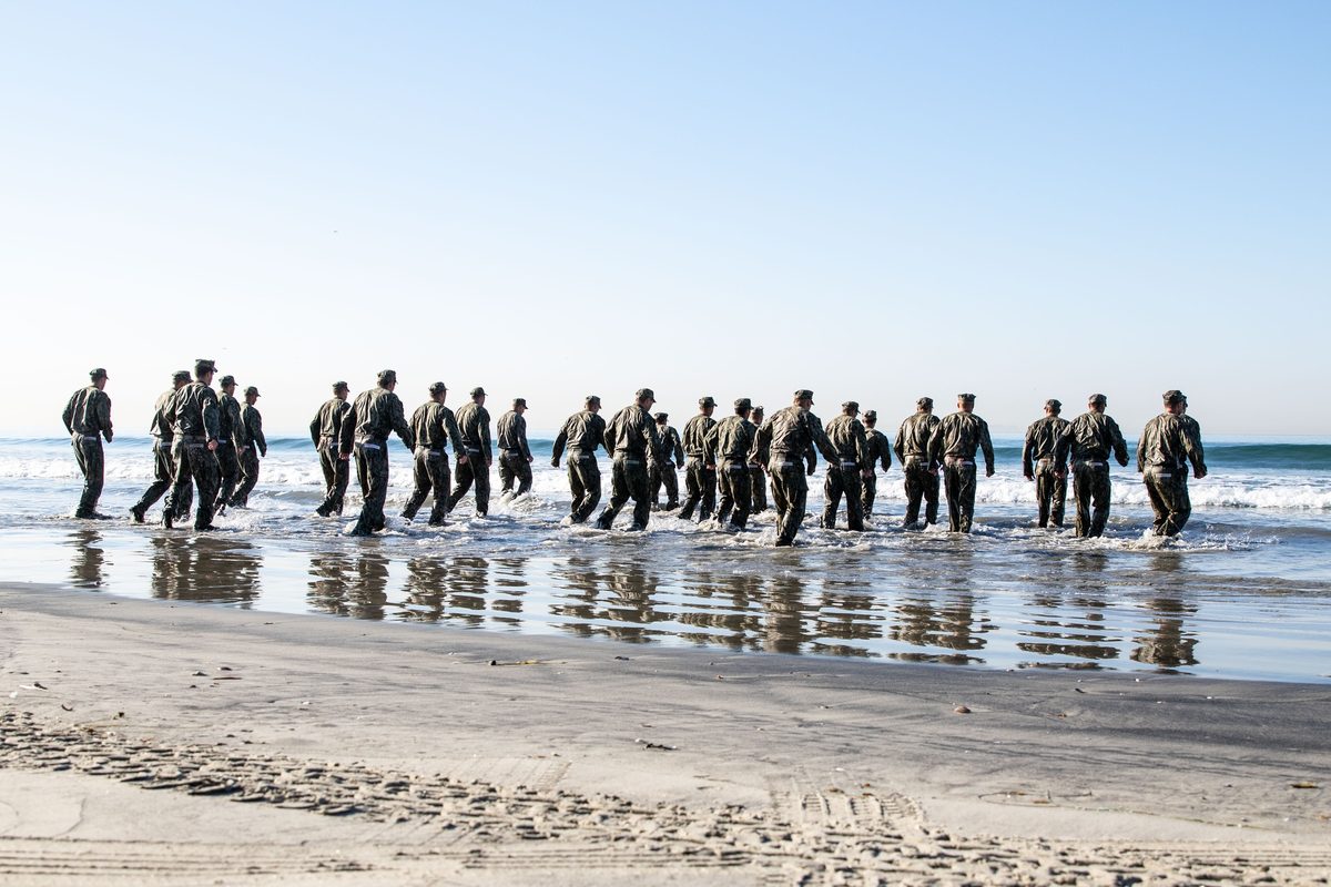 Navy SEAL candidates run into the Pacific surf during BUD/S training