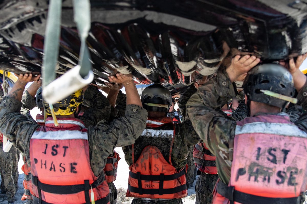 Navy SEAL candidates carry an inflatable boat during BUD/S training