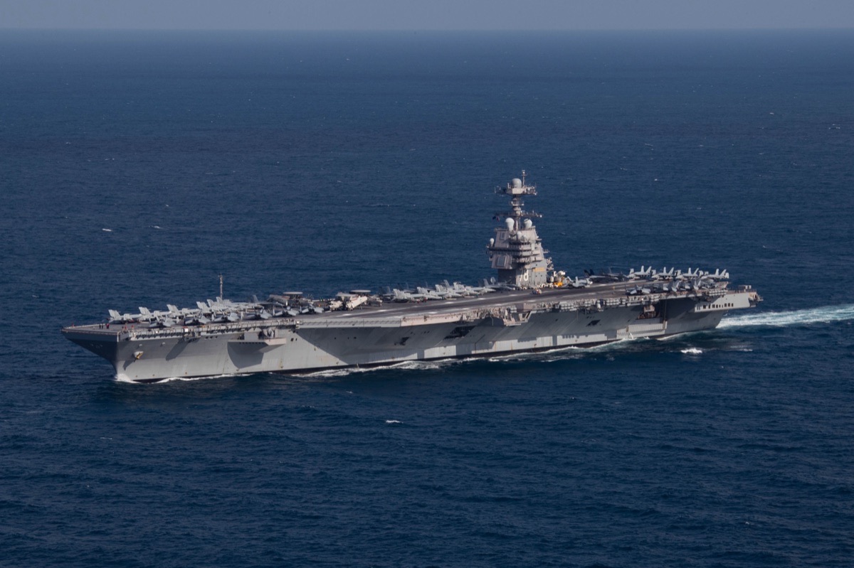 USS Gerald R. Ford aircraft carrier underway at sea, with aircraft visible on the flight deck and the carrier's island superstructure prominent