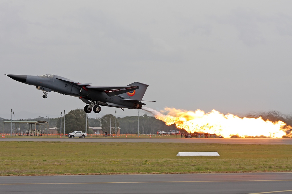 RAAF F-111 performing a dump and burn maneuver with a massive wall of flame trailing behind the aircraft