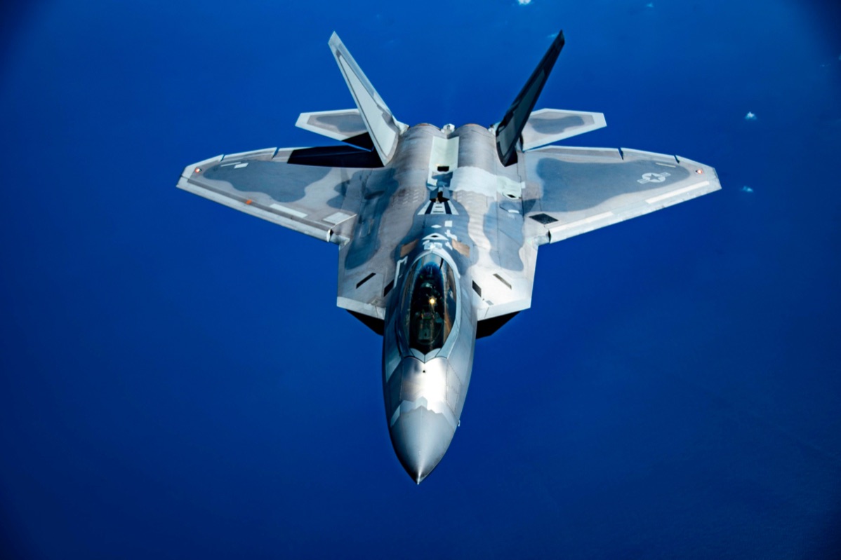 F-22 Raptor approaching a KC-135 Stratotanker refueling boom over the ocean, demonstrating the aircraft's aerial refueling capability