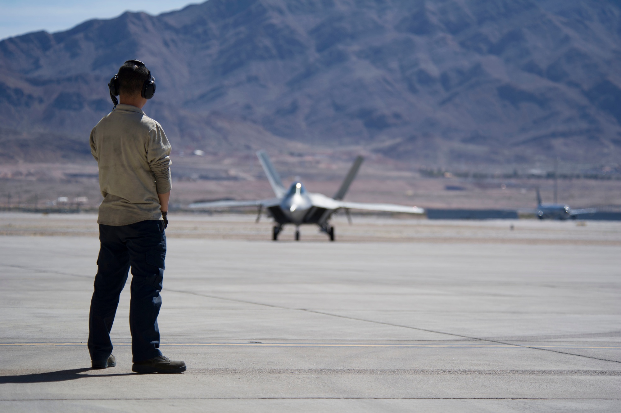 Maintenance crew working on an F-22 Raptor's radar-absorbent coating in a hangar