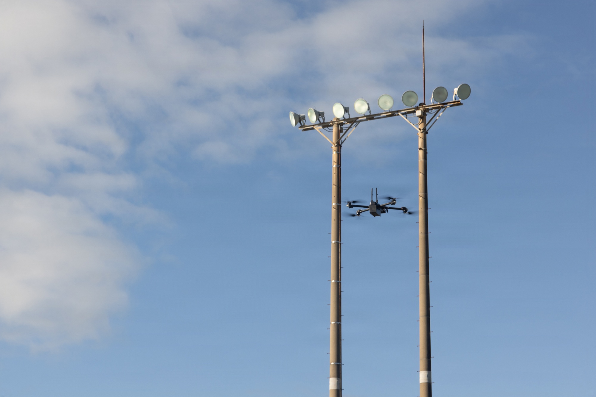 An FPV drone in flight with a barely visible fiber-optic cable trailing behind it
