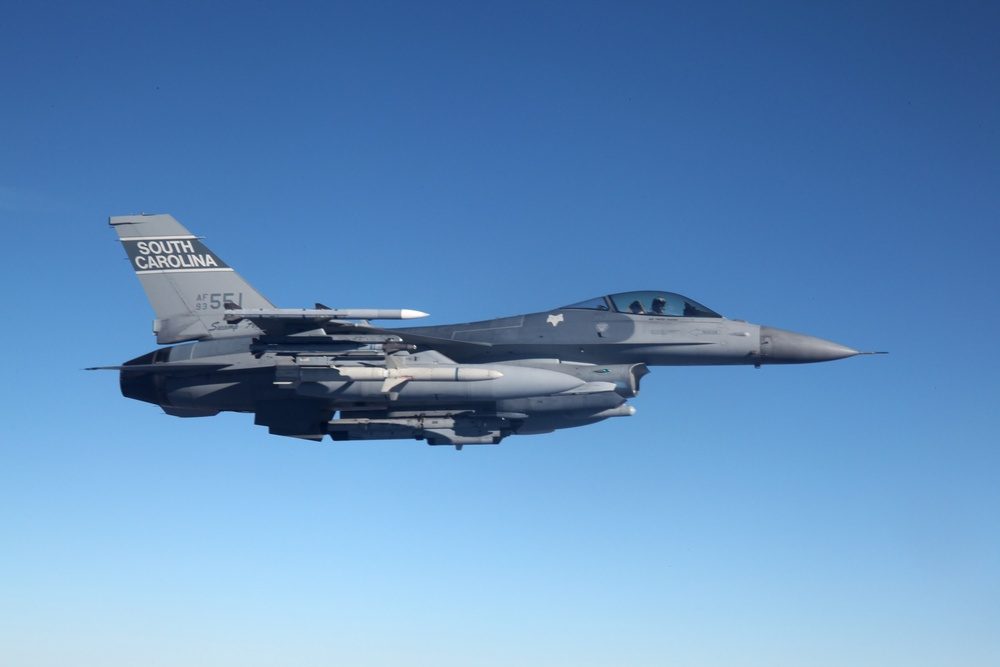 F-16 Fighting Falcon in flight armed with missiles against blue sky
