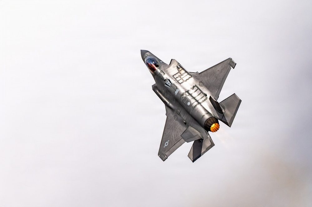 F-35A Lightning II in flight with afterburner lit against blue sky