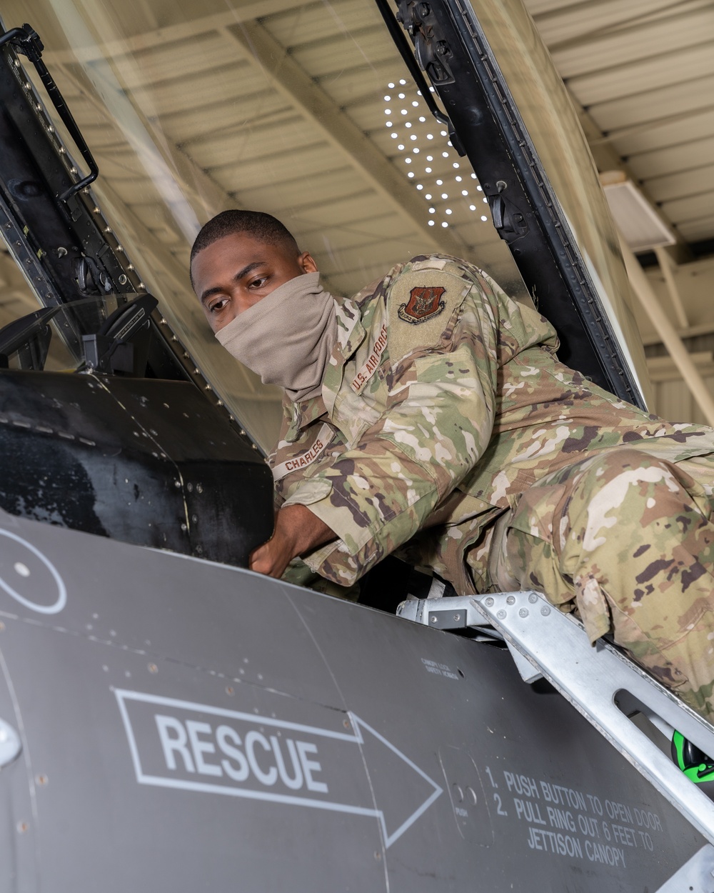 Avionics technician inspecting the cockpit instrument panel of an F-16 Fighting Falcon, showing the complex displays pilots must interpret during combat