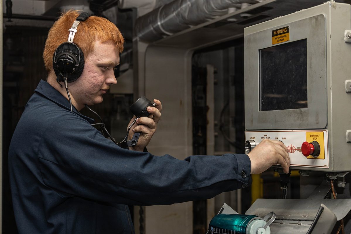 A sailor operating an advanced electromagnetic weapons elevator in the hangar bay of USS Gerald R. Ford