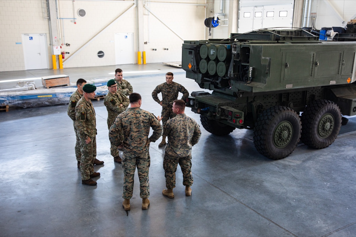 U.S. Marines and Lithuanian soldiers surrounding a HIMARS launcher inside a hangar during a reload demonstration