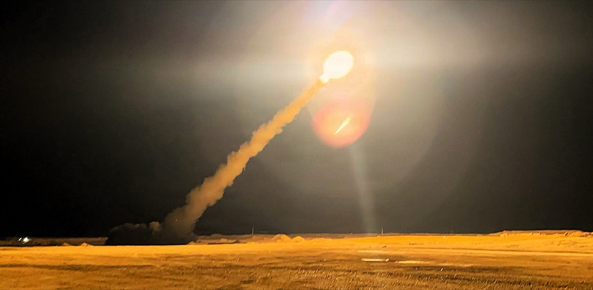 HIMARS launching rockets at night with bright launch flame visible against the dark sky