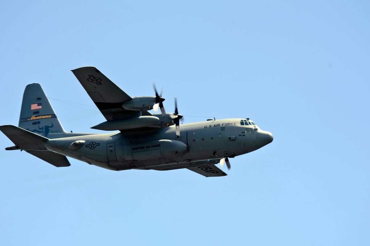 C-130 Hercules aircraft approaching Khe Sanh combat base runway for a resupply drop with smoke from artillery impacts visible