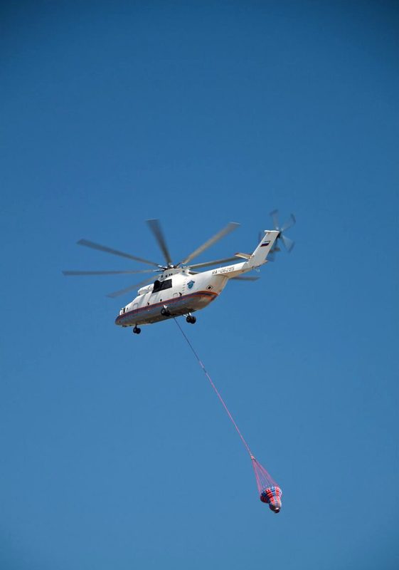 Mi-26 Halo helicopter in flight carrying a sling load during firefighting operations