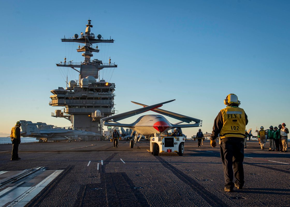 MQ-25 Stingray drone positioned on a carrier flight deck with crew nearby