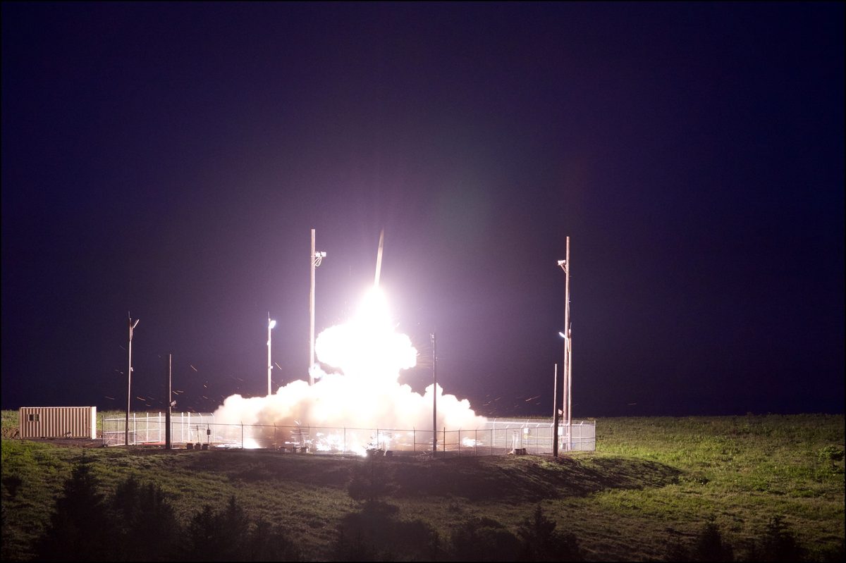 THAAD interceptor launching at night with bright exhaust plume illuminating the launch site