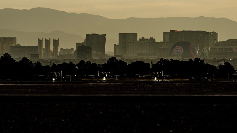 A-10 Warthog aircraft lined up on a flight line with the Las Vegas skyline in the background