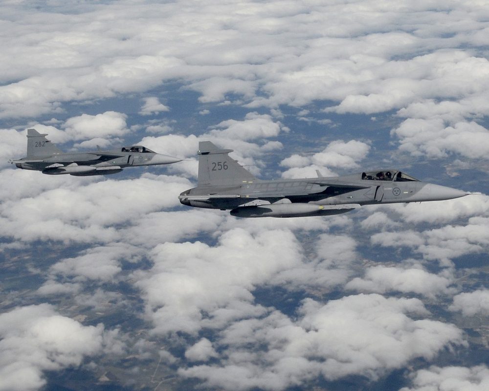 Two Swedish Air Force Gripens in formation flight above clouds