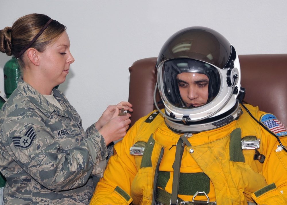 U-2 pilot in yellow pressure suit with helmet being fitted by support crew