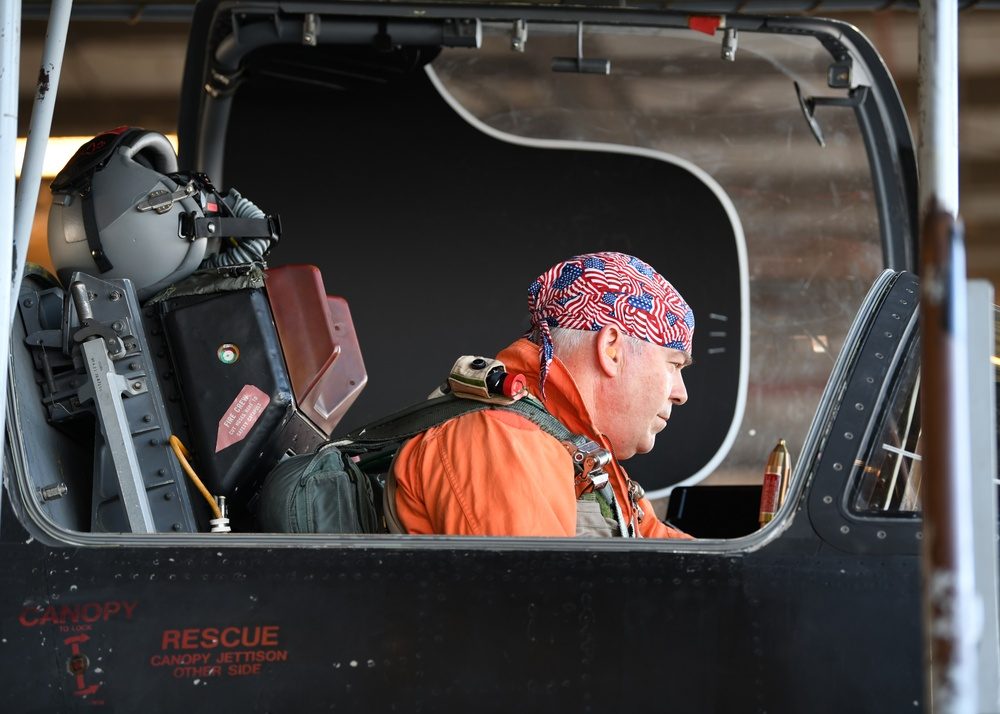 U-2 instructor pilot in orange pressure suit performing preflight checks in the cockpit