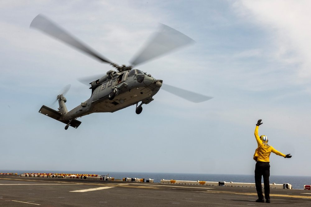 MH-60 Sea Hawk helicopter landing on a Wasp-class flight deck with landing signal enlisted guiding