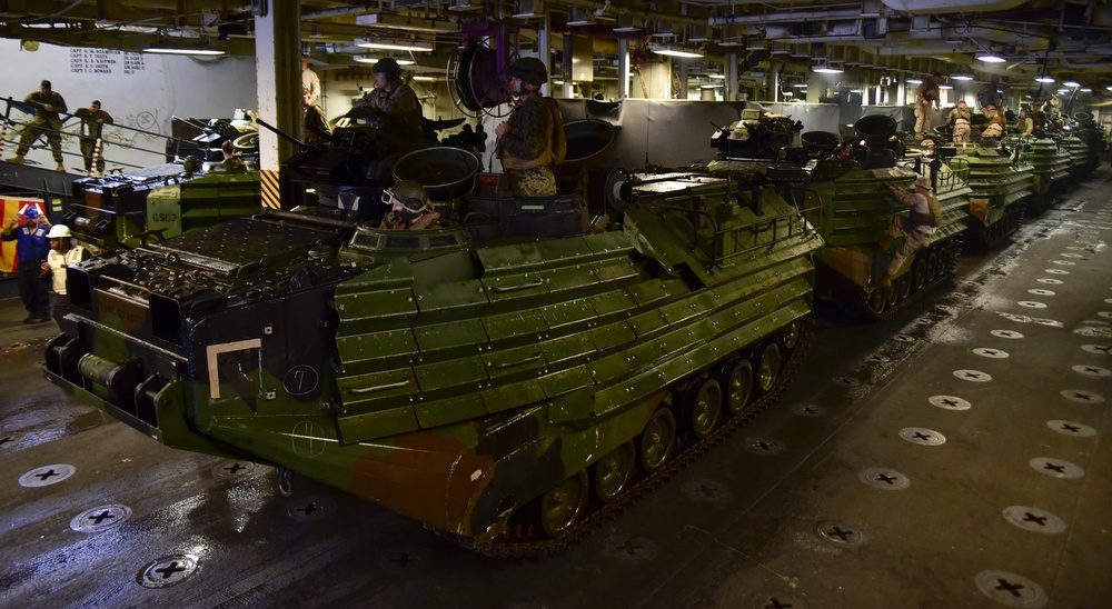 Marine amphibious assault vehicles parked inside the well deck of a Wasp-class ship